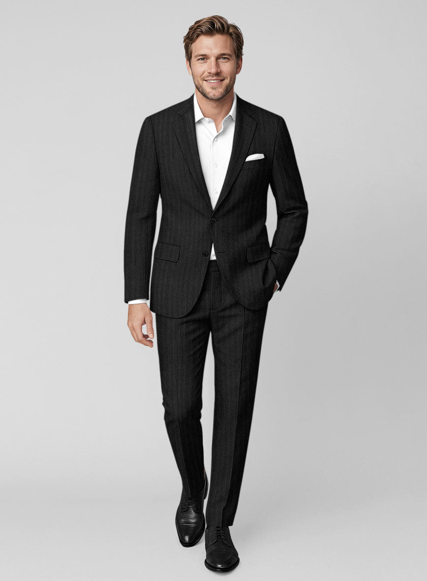 Man wearing a black herringbone wool suit with white shirt and pocket square, full-length view