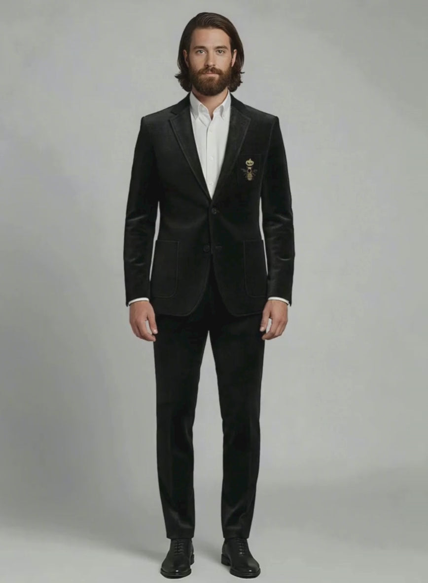 Man wearing a black velvet suit with embroidered golden bee crest on the chest pocket