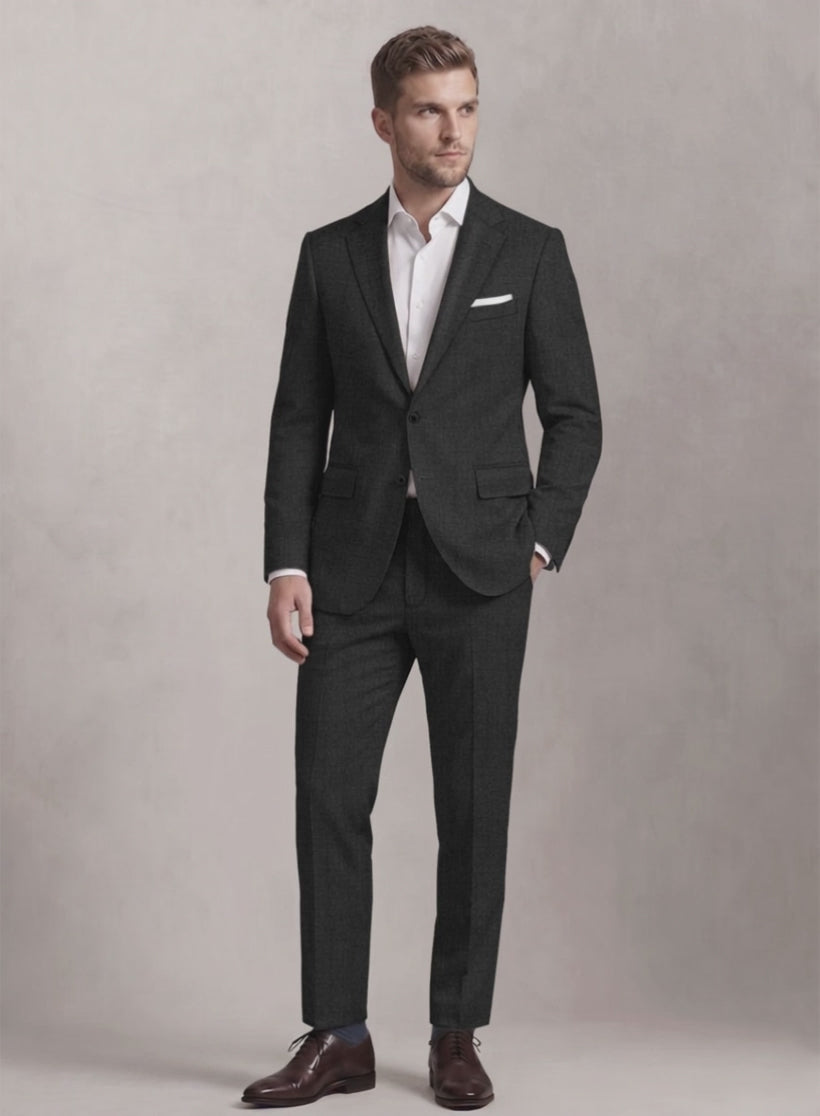 Man wearing a dark charcoal textured wool suit with white shirt, hand in pocket