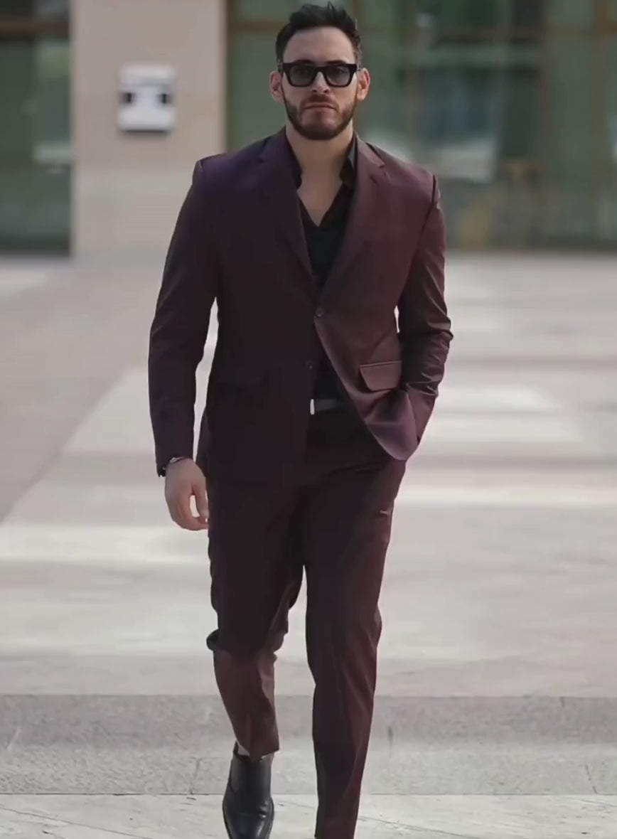 Man walking outdoors in a burgundy two-button suit with a black shirt and sunglasses