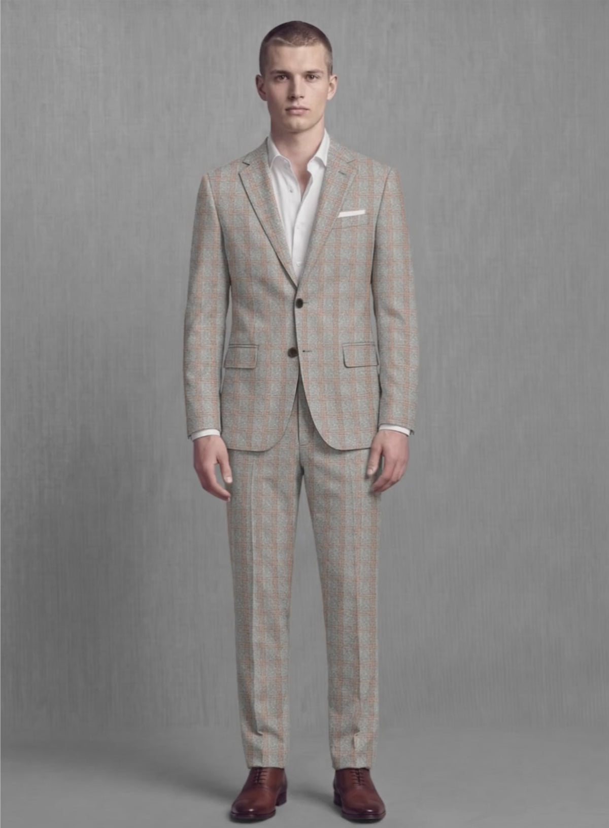 Man wearing a slate and rust check soft tweed suit, front view with white pocket square