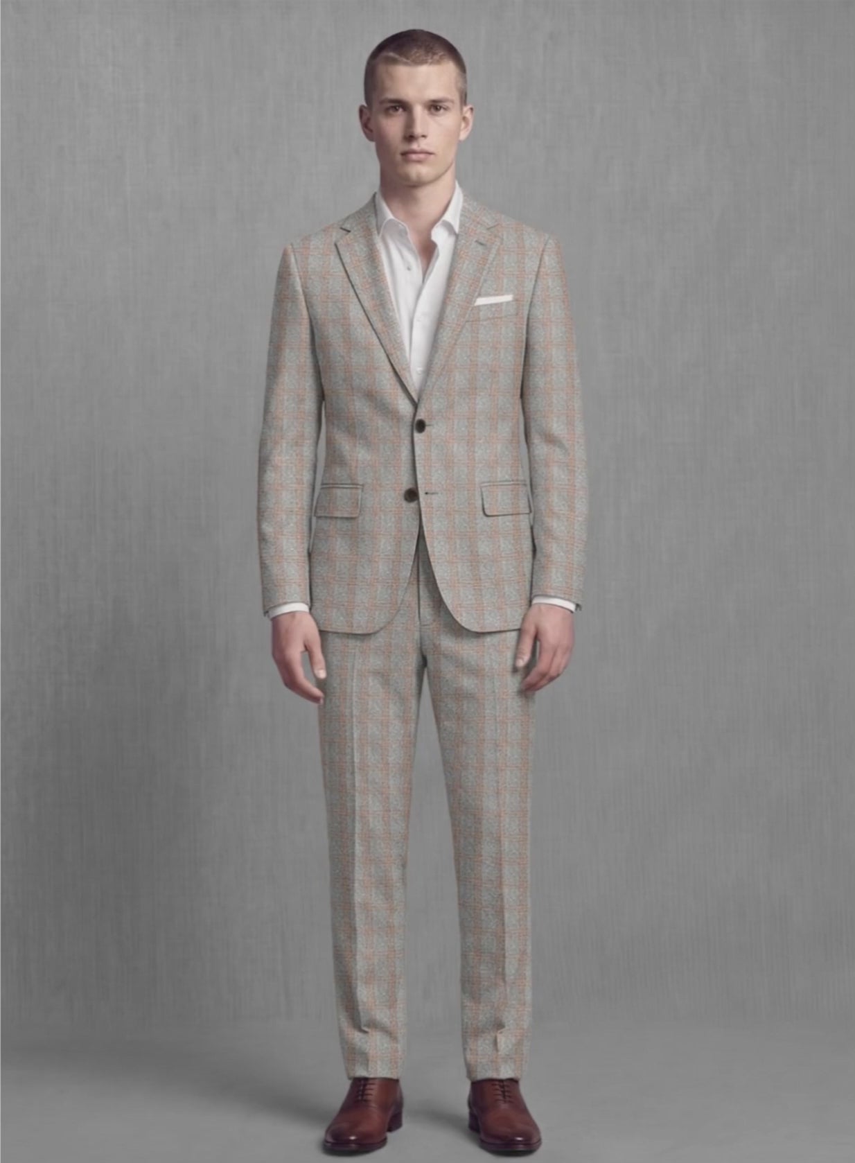 Man wearing a slate and rust check soft tweed suit, front view with white pocket square