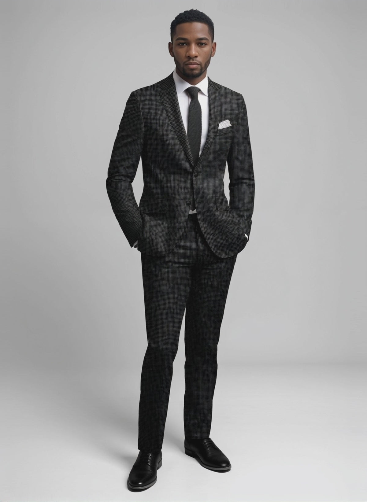Man wearing a charcoal houndstooth wool suit with a black knit tie and pocket square