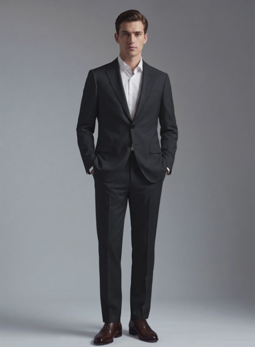 Man wearing a charcoal black wool suit with two-button jacket, hands in pockets